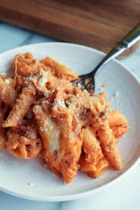 Single serving of creamy baked ziti on a white plate with a sprinkle of parmesan cheese