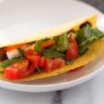 Oven baked taco with lettuce and tomatoes on a white plate