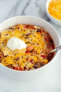 bowl of taco soup with cheese, sour cream and tortilla chips on top