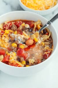 Taco soup with sour cream and shredded cheese all stirred into the hot soup