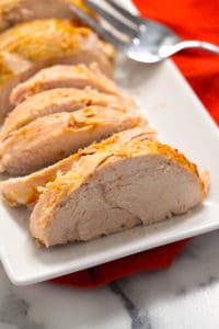 A white serving platter with 8 pieces of sliced turkey breast and a large serving fork.