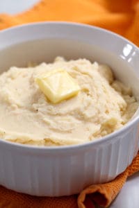 white bowl filled with slow cooker mashed potatoes and butter on top