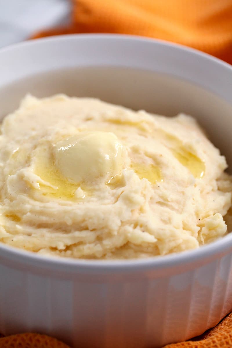 creamy mashed potatoes with butter that's melting on top in a white bowl