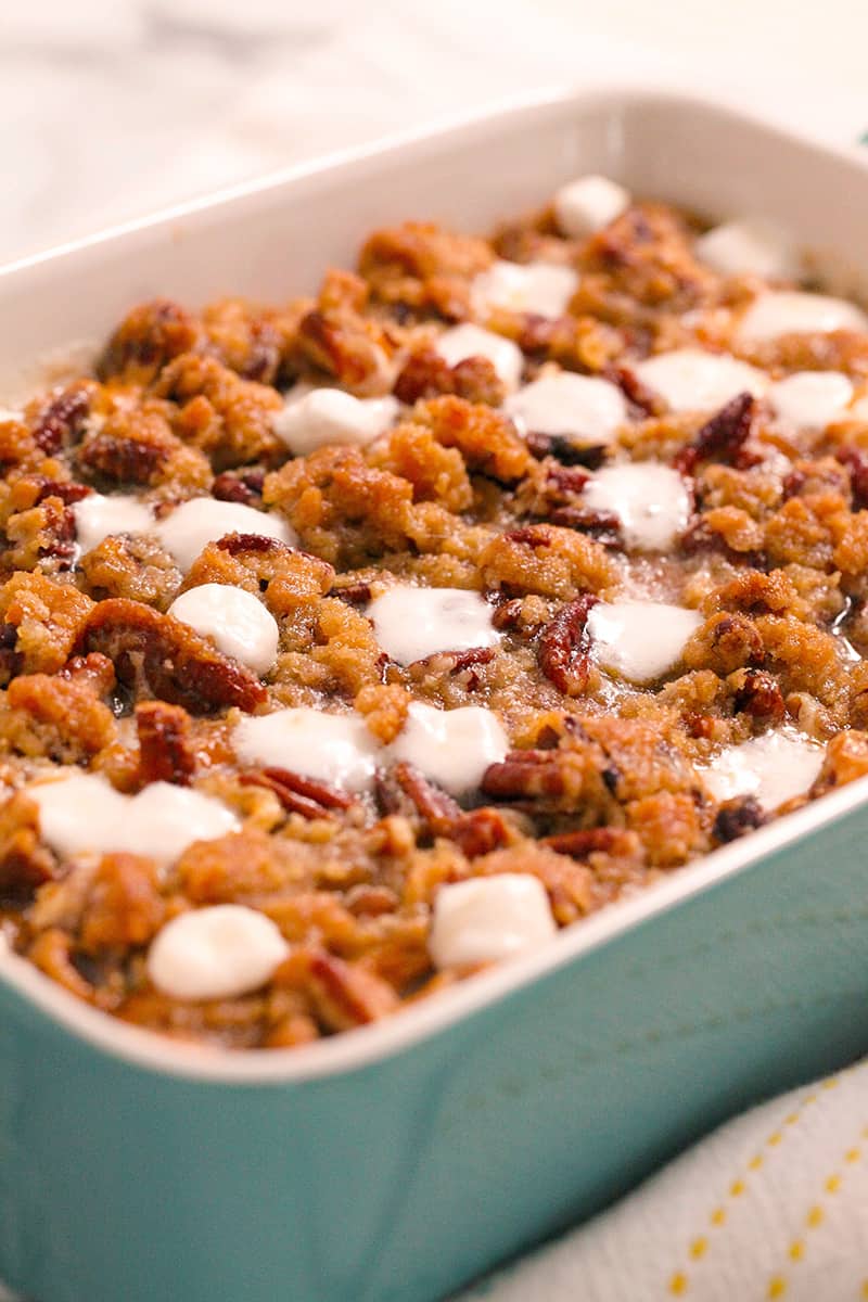 Casserole dish with sweet potato casserole and a crunchy pecan topping and melted marshmallows