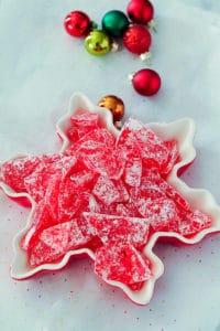an aerial view of a snowflake dish filled with cinnamon rock candy and miniature ornaments in the background