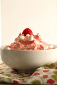 Strawberry jello salad topped with marshmallows and strawberries