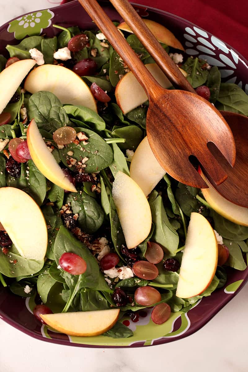 autumn spinach salad on a salad plate with tongs