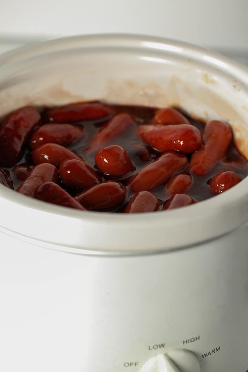small white slow cooker full of barbecue little smokies